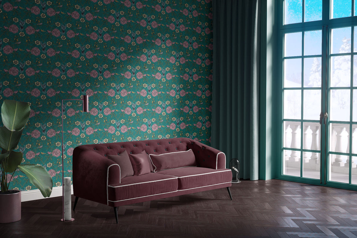 teal_A roll of wallpaper featuring a floral and bird pattern on a teal background in a room with a maroon couch.