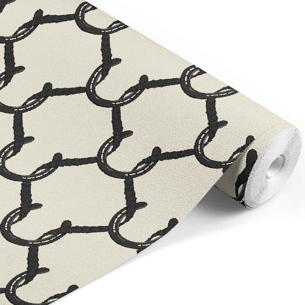 black_A roll of wallpaper with a beige and black geometric pattern featuring shapes resembling horseshoes, consistent with equestrian themes.